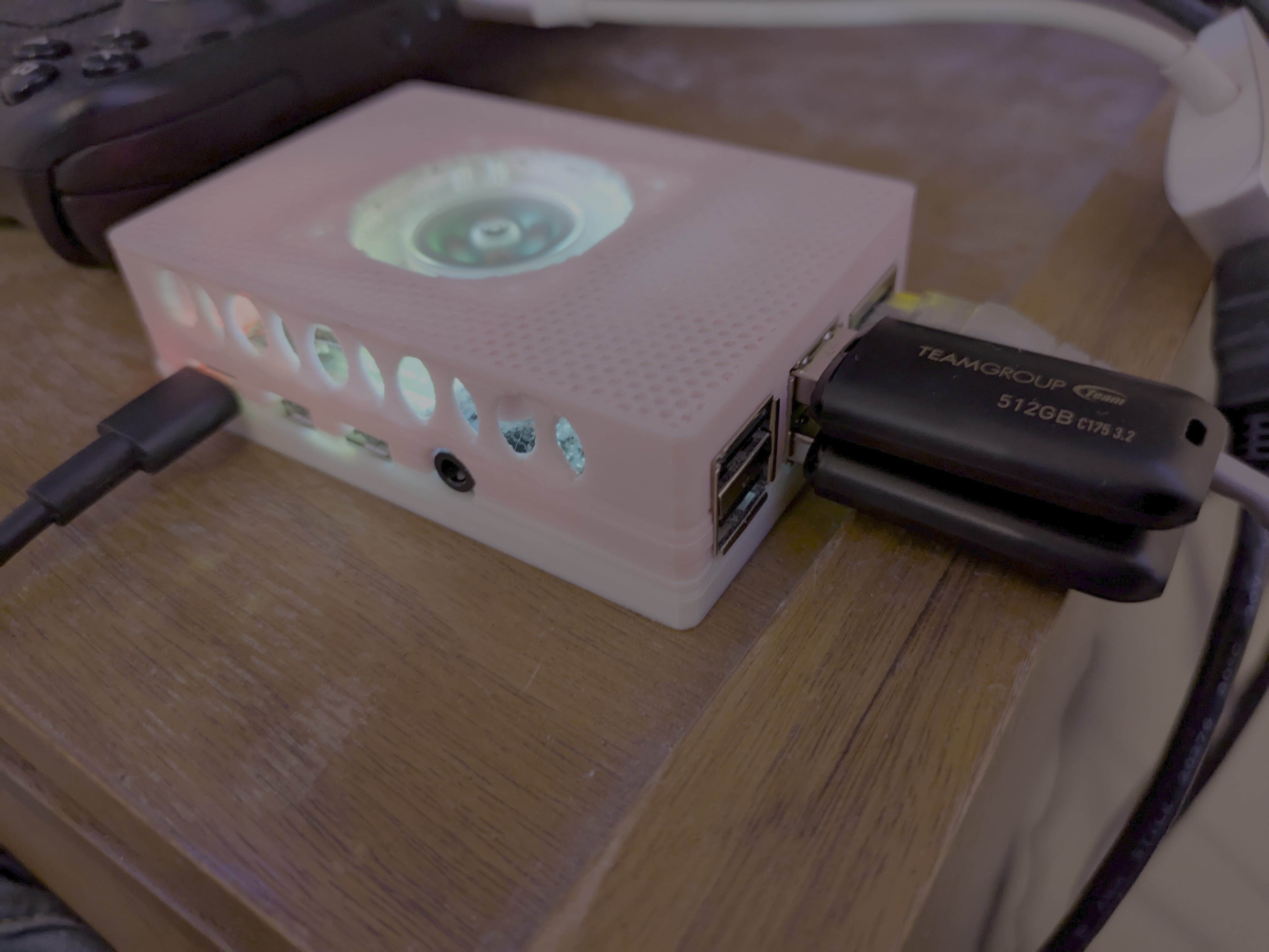 A photo of a Raspberry Pi 4 in a pink and white 3D printed case, with two 512 GB USB sticks coming out of it.